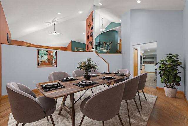 dining area featuring ceiling fan, high vaulted ceiling, and light hardwood / wood-style flooring