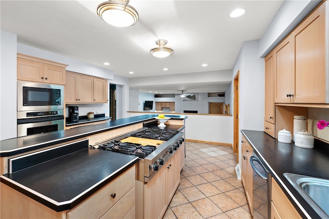 kitchen featuring light brown cabinets, ceiling fan, a kitchen island, appliances with stainless steel finishes, and light tile patterned flooring