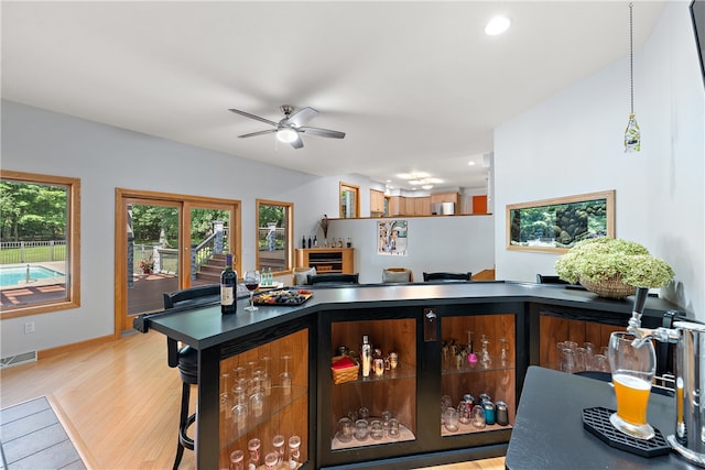 kitchen featuring light hardwood / wood-style flooring, ceiling fan, a breakfast bar, and hanging light fixtures