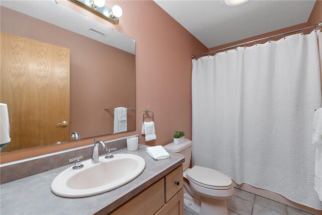 bathroom with toilet, vanity, and tile patterned floors