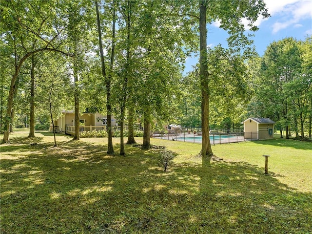 view of yard featuring an outdoor pool, an outdoor structure, and fence