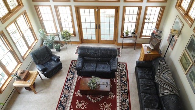 living room featuring french doors, a baseboard heating unit, a towering ceiling, and light tile patterned flooring