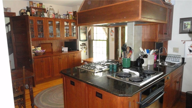 kitchen featuring oven, sink, stainless steel cooktop, custom exhaust hood, and hardwood / wood-style flooring