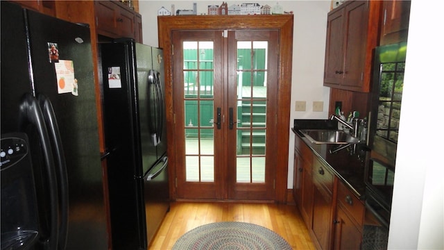 kitchen with french doors, light hardwood / wood-style flooring, sink, and black refrigerator