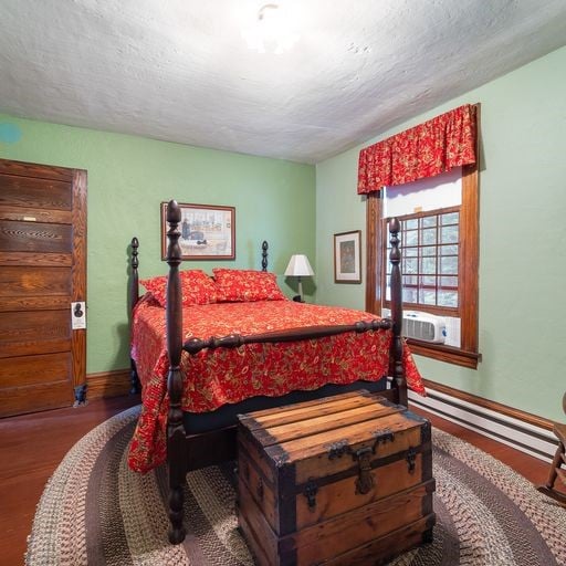 bedroom with cooling unit, hardwood / wood-style floors, a textured ceiling, and a baseboard heating unit