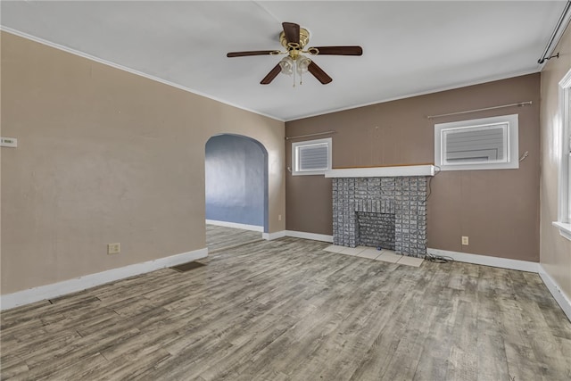 unfurnished living room featuring a fireplace, ceiling fan, hardwood / wood-style floors, and crown molding