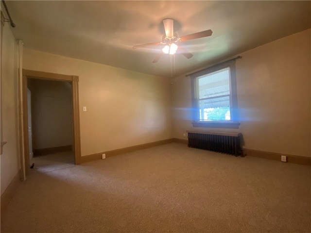 carpeted spare room with radiator and ceiling fan