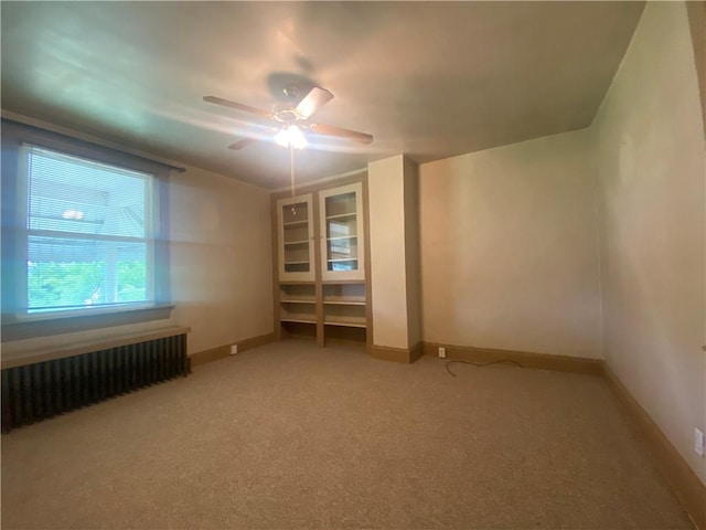 empty room featuring carpet, radiator, and ceiling fan