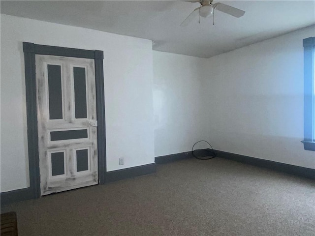 empty room with ceiling fan and dark carpet