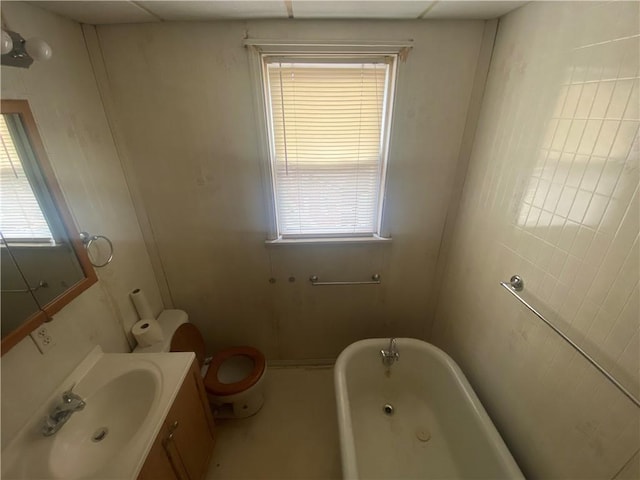 bathroom featuring vanity, a tub to relax in, and toilet