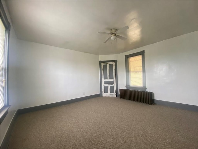 empty room featuring radiator, ceiling fan, and dark colored carpet