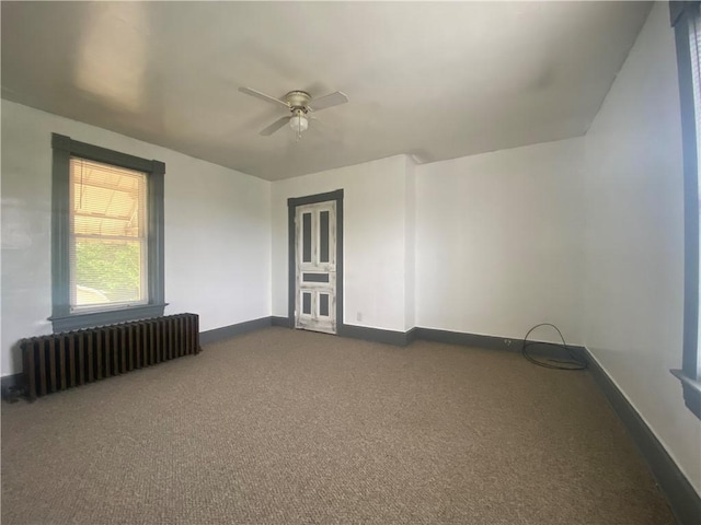 empty room with radiator, dark carpet, and ceiling fan