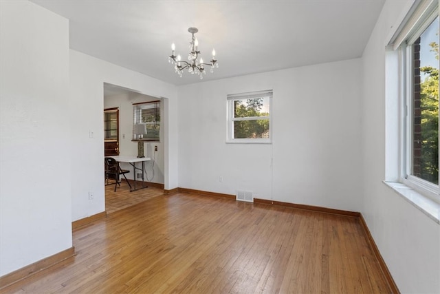 spare room featuring light hardwood / wood-style floors and a notable chandelier