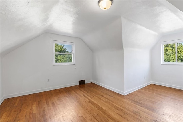 bonus room with vaulted ceiling, plenty of natural light, and light hardwood / wood-style floors