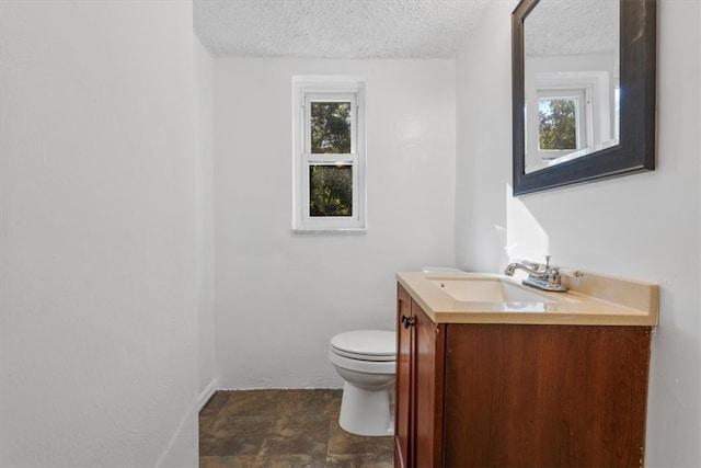 bathroom featuring a textured ceiling, toilet, a healthy amount of sunlight, and vanity