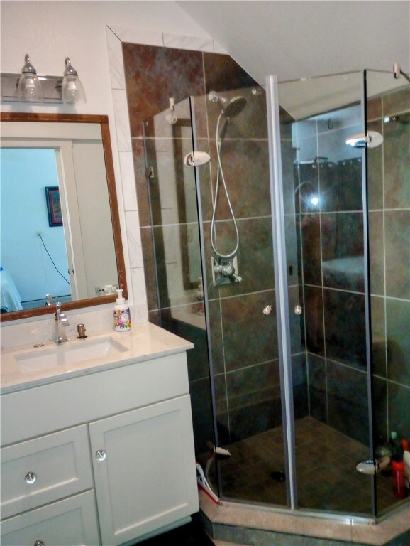 bathroom featuring a shower with shower door and vanity