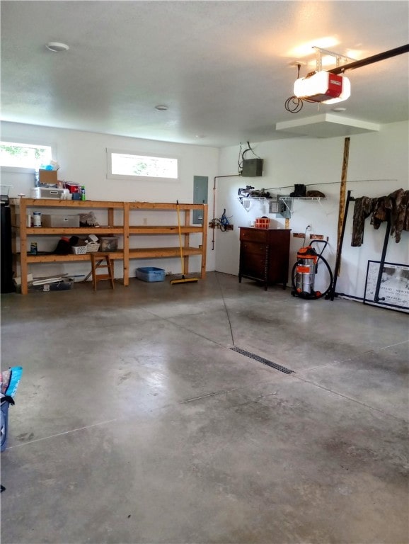 garage with a garage door opener, a workshop area, and electric panel