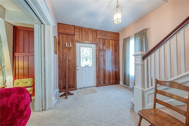 carpeted foyer entrance featuring wood walls