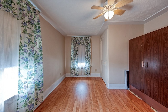 unfurnished room with ceiling fan, light hardwood / wood-style floors, and a textured ceiling