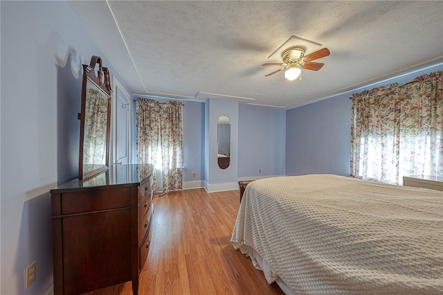 bedroom with a textured ceiling, light hardwood / wood-style flooring, and ceiling fan