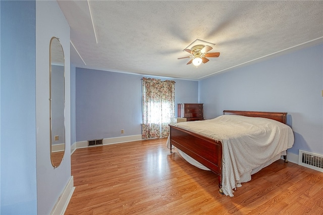 bedroom with ceiling fan, light hardwood / wood-style floors, and a textured ceiling