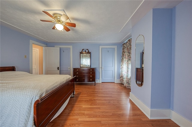 bedroom featuring ceiling fan, light wood-type flooring, and a textured ceiling