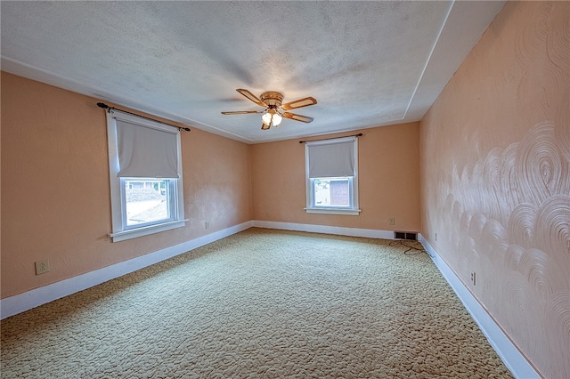 carpeted spare room with ceiling fan, a textured ceiling, and a healthy amount of sunlight