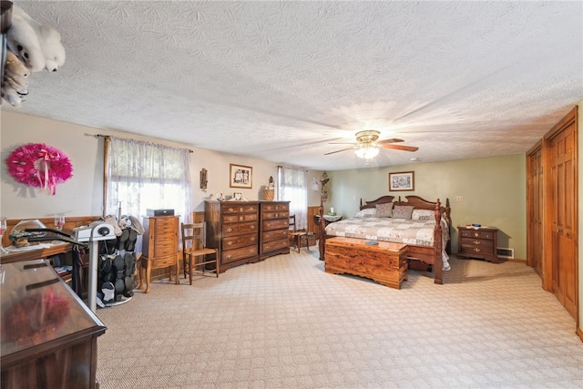 carpeted bedroom featuring ceiling fan, a textured ceiling, and multiple windows