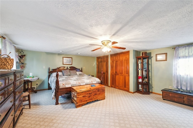 bedroom featuring ceiling fan, a closet, a textured ceiling, and light carpet