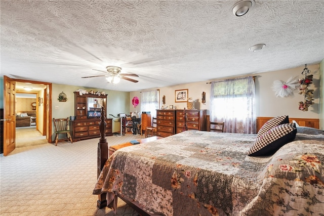 bedroom featuring ceiling fan, a textured ceiling, light carpet, and multiple windows