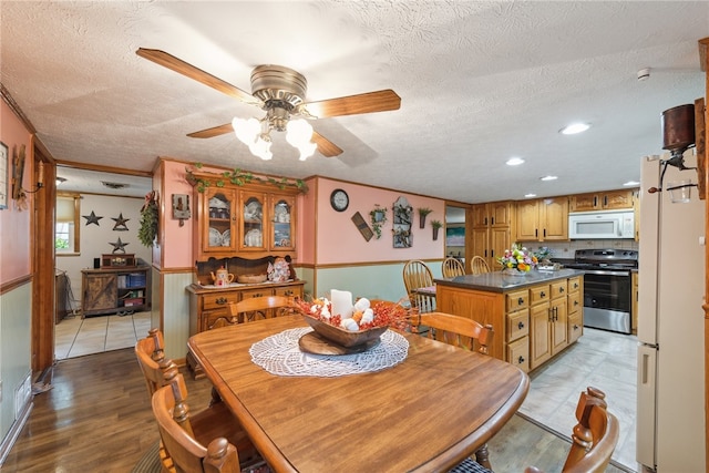 dining area featuring ceiling fan, light hardwood / wood-style floors, and a textured ceiling