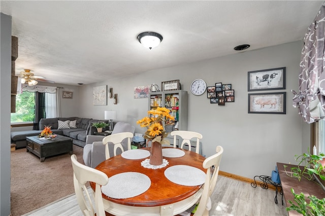 dining area with a textured ceiling, ceiling fan, and light wood-type flooring