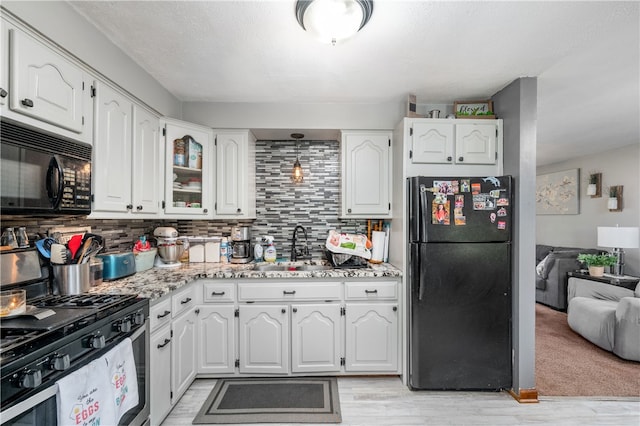 kitchen with black appliances, backsplash, light hardwood / wood-style floors, sink, and white cabinetry