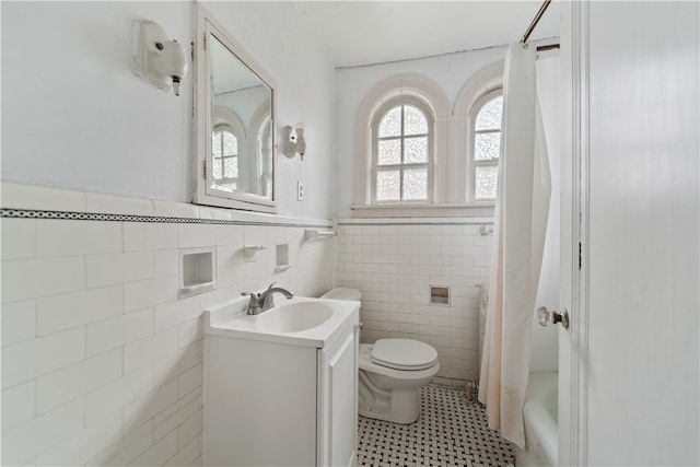 full bathroom featuring vanity, shower / bath combo with shower curtain, tile patterned flooring, and tile walls