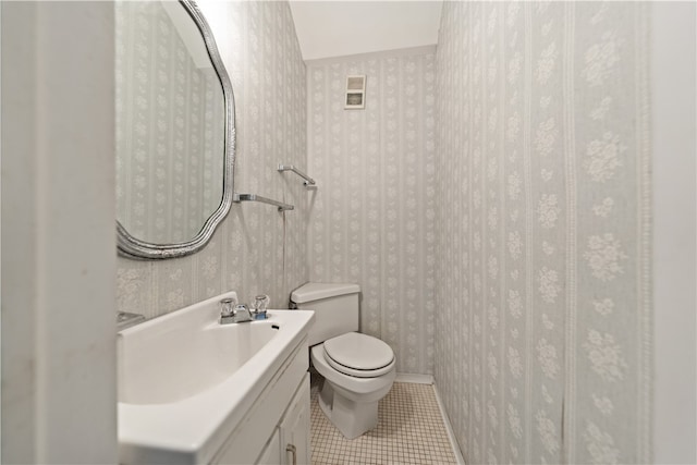 bathroom with toilet, vanity, and tile patterned floors