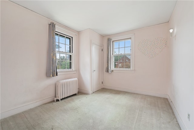 empty room with light colored carpet and radiator