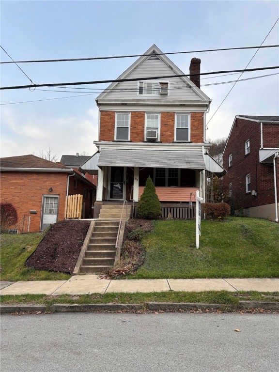 view of front facade with covered porch, a front lawn, and cooling unit