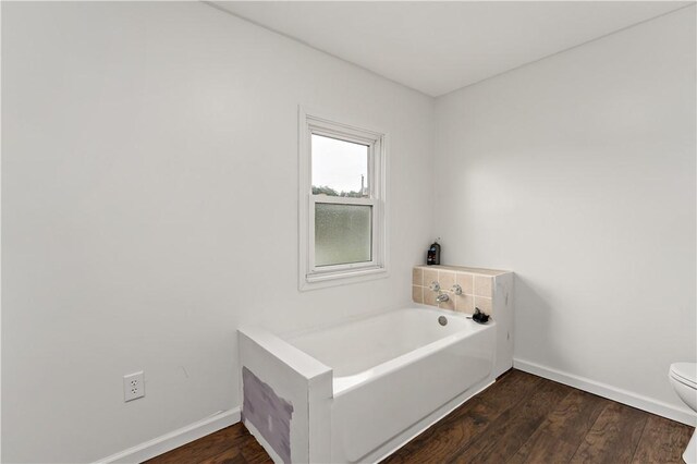 bathroom featuring a tub, hardwood / wood-style floors, and toilet