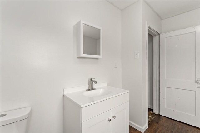 bathroom featuring toilet, vanity, and wood-type flooring