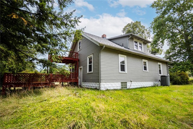 rear view of house featuring a deck, central AC unit, and a lawn