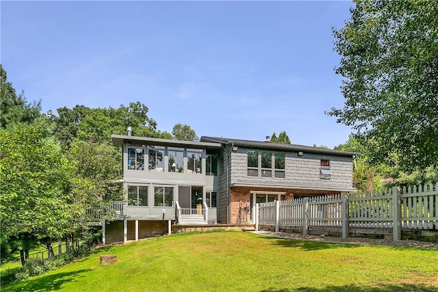 back of property featuring a lawn, brick siding, and fence