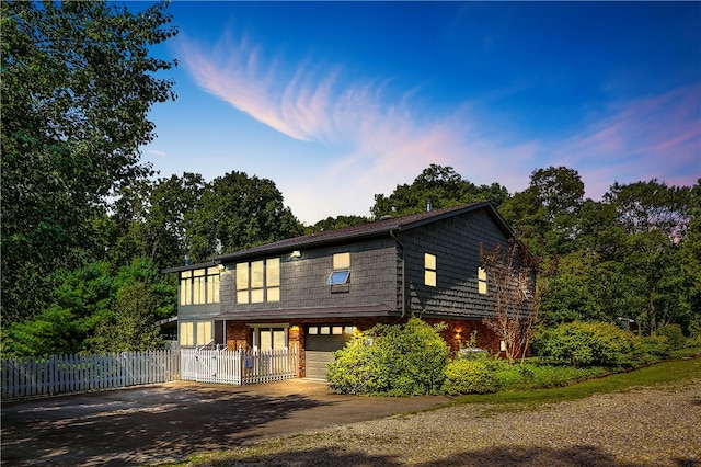 view of front of house with brick siding, an attached garage, driveway, and fence