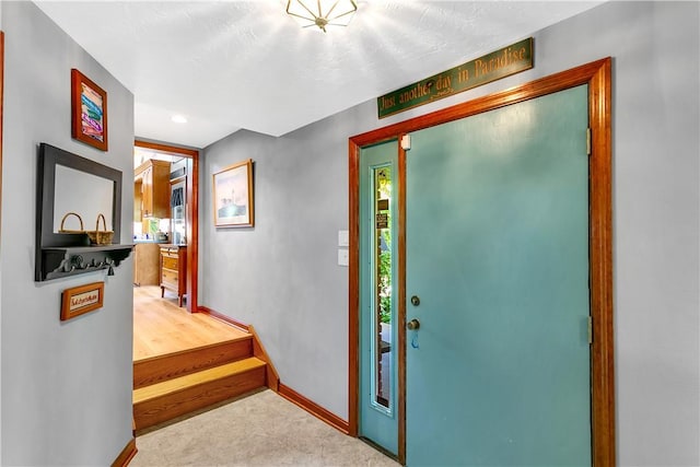 carpeted foyer featuring baseboards