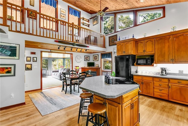 kitchen with ceiling fan, black appliances, wooden ceiling, light wood-type flooring, and a center island