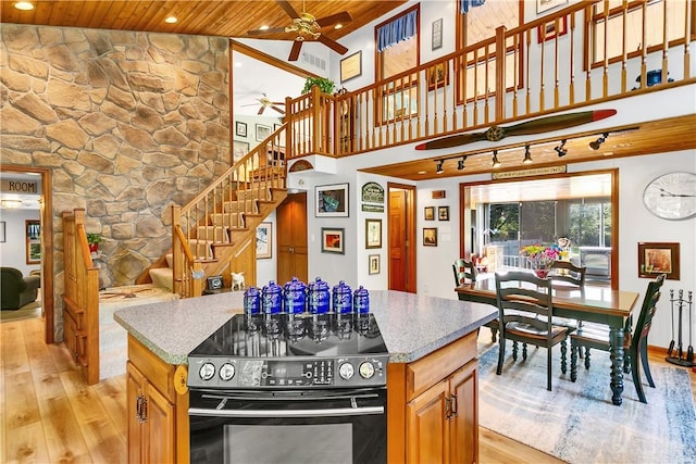 kitchen featuring a ceiling fan, wood ceiling, black range with electric stovetop, light wood-type flooring, and a center island