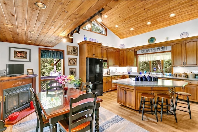 kitchen with freestanding refrigerator, track lighting, wooden ceiling, brown cabinets, and a center island