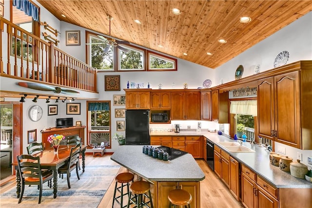 kitchen with light wood finished floors, a kitchen bar, wooden ceiling, black appliances, and a sink