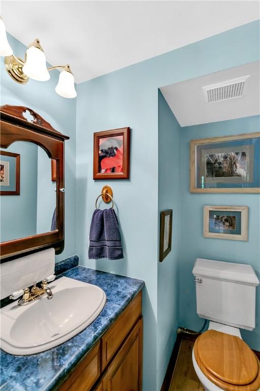 half bathroom with visible vents, toilet, and vanity