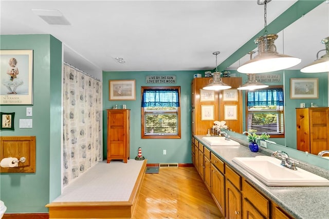 bathroom featuring double vanity, wood finished floors, visible vents, and a sink