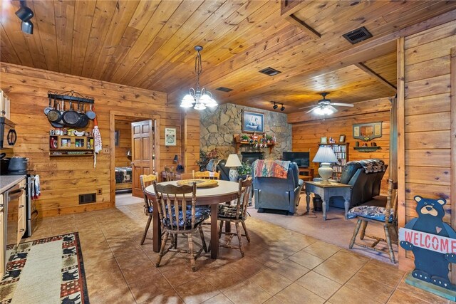 dining space featuring wood ceiling, wooden walls, ceiling fan with notable chandelier, and light tile patterned floors